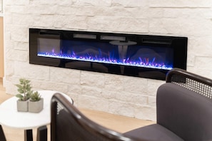 A modern fireplace with a glass front, set in a white stone wall. - The Belmont - Kierland (Scottsdale)