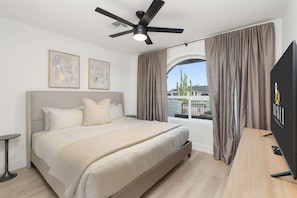 A modern bedroom with a large bed, a ceiling fan, and a TV on a wooden desk. - The Belmont - Kierland (Scottsdale)