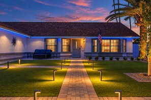 A house with a tiled roof, a front porch with a bench, and a well-lit pathway leading to the entrance. - NEW Alta Mesa Retreat Pool Games More Sleeps 10 (Mesa)