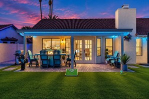 Una casa amb un porxo cobert, mobiliari d'exterior i un jardí ben cuidat.