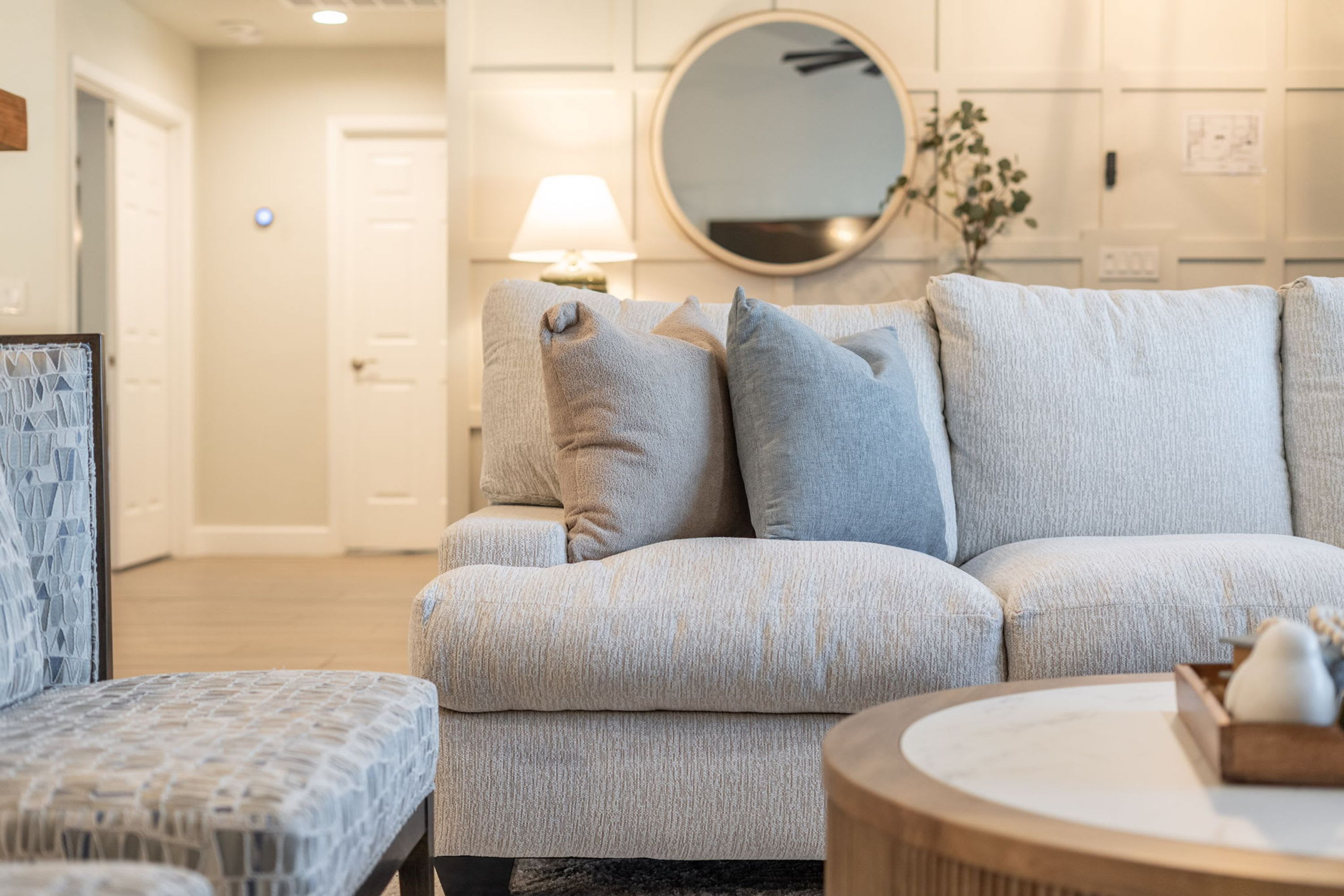 A modern living room with a grey sofa set, a patterned armchair, and a round coffee table.