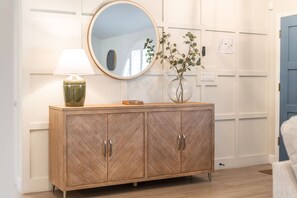 A wooden cabinet with two doors, a round mirror above it, and a vase with plants on top. - NEW Sonoran Sol Modern Pool Oasis Near Kierland (Scottsdale)