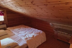 Ein Einzelbett mit weißer Decke in einem Holzhüttenraum mit schrägem Dach.