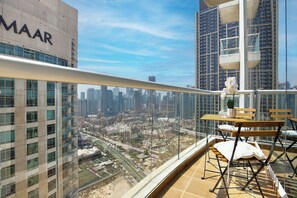 A balcony with a view of a cityscape, a table with chairs, and a potted plant. - Luxury1BR in Downtown/Next Dubai Mall & Burj Khalifa (Dubai)