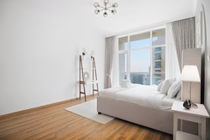 A modern bedroom with a large bed, a desk with a lamp, a window with curtains, and a view of a cityscape. - Luxury1BR in Downtown/Next Dubai Mall & Burj Khalifa (Dubai)