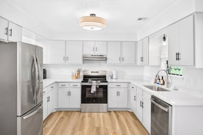 A modern kitchen with white cabinetry, stainless steel appliances, and a wooden floor. - Near 17 Springs Spacious 3BR Millbrook Home (Millbrook)