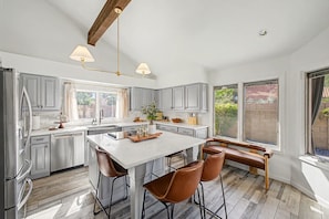 A modern kitchen with a central island, bar stools, and a view of the outdoors. - NEW Royal Palms Retreat Pool Spa Pool Table (Tempe)