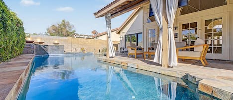 A swimming pool with a pergola and outdoor seating area.