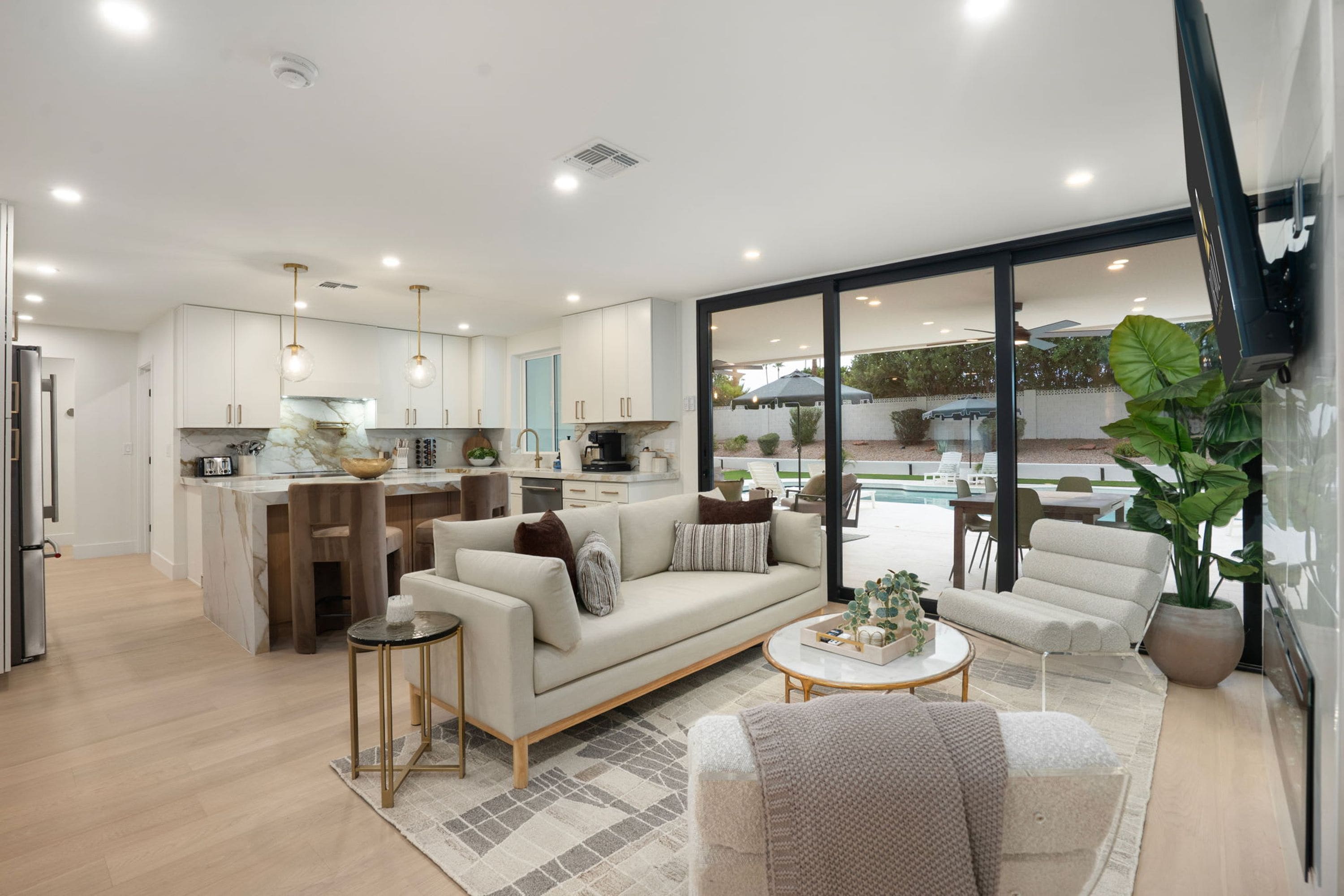 Un espace de vie moderne comprenant une cuisine, un coin repas et donnant sur une piscine.