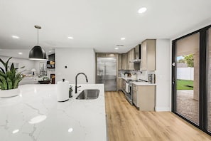 A modern kitchen with a marble countertop, stainless steel appliances, and a sliding glass door leading to a backyard. - NEW The Fairmont Kierland Pool Spa Daybeds (Scottsdale)