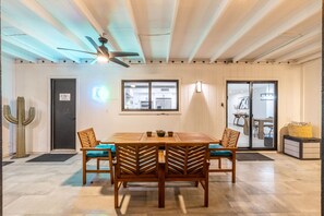 A dining area with a wooden table and chairs, a ceiling fan, and a view of the kitchen through a glass door. - The Brexton Luxe Scottsdale Resort-style Oasis (Scottsdale)