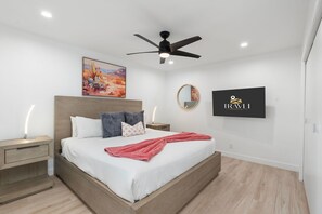 A modern hotel room with a bed, a ceiling fan, a painting, a mirror, and a TV displaying a logo. - The Brexton Luxe Scottsdale Resort-style Oasis (Scottsdale)