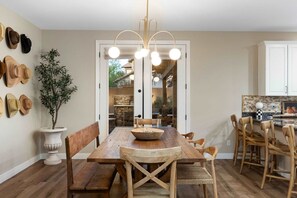 A dining area with a wooden table, chairs, and a hanging light fixture. - NEW Lone Mtn Estate Resort-style Oasis Sleeps 14 (Cave Creek)