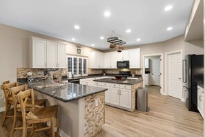 A spacious kitchen with white cabinets, a granite countertop, and a stone backsplash. - NEW Lone Mtn Estate Resort-style Oasis Sleeps 14 (Cave Creek)
