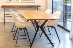 A rectangular wooden table with black metal legs, surrounded by four white chairs with black metal legs. - NEW Desert Bloom Pool Spa Game Room (Scottsdale)