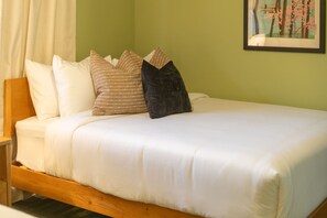 A bed with white bedding and multiple pillows, a wooden headboard, and a framed picture on the wall. - NEW Desert Bloom Pool Spa Game Room (Scottsdale)