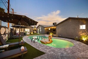 Ein Garten mit Swimmingpool, Liegestühlen und Grillplatz.