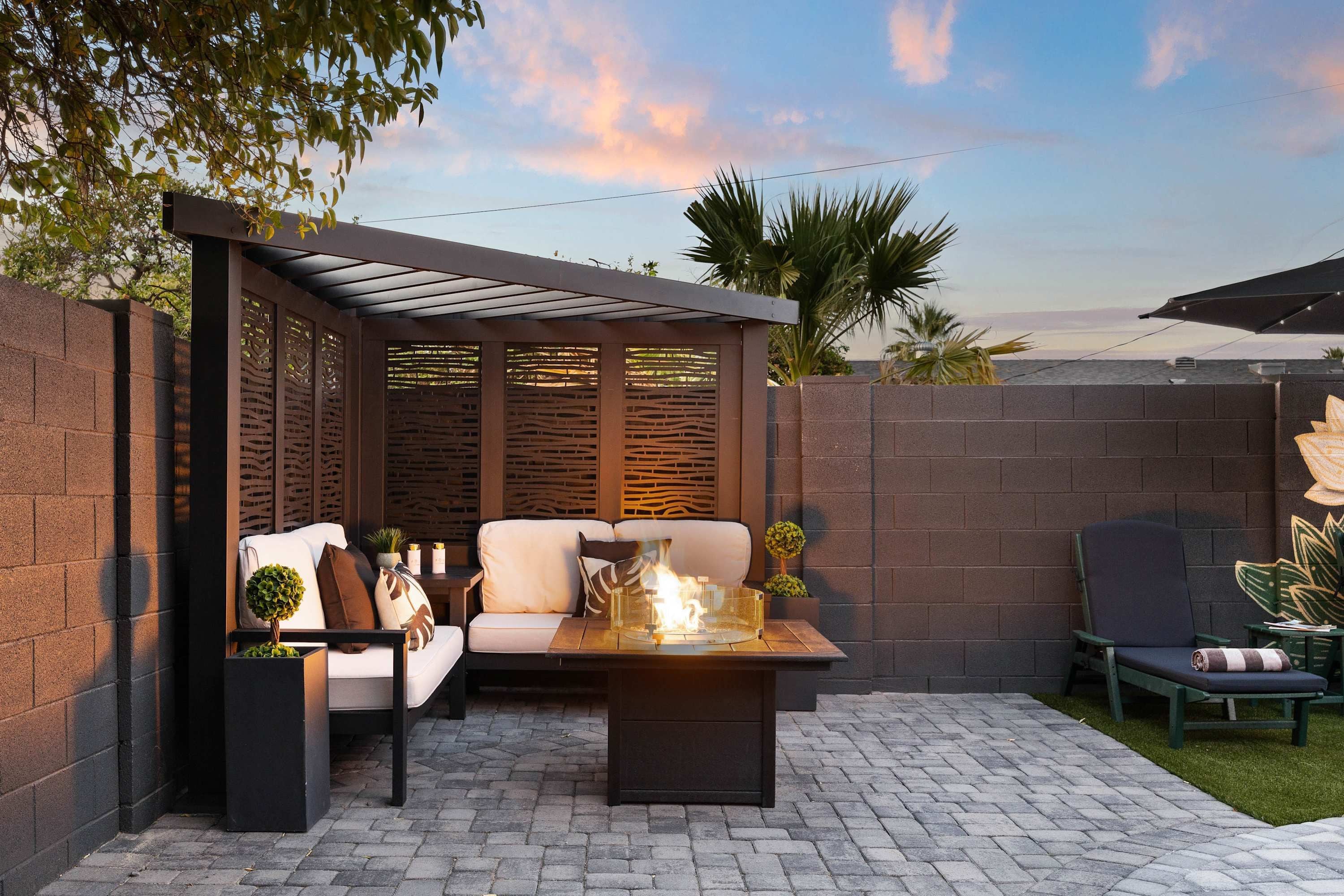 A patio with a seating area, a fire feature, and a view of the sea.