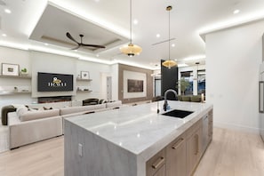 A modern kitchen with a large island, built-in appliances, and a dining area with a sofa and table. - Mariposa Social Luxe Old Town Villa (Scottsdale)