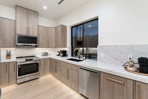 Eine moderne Küche mit Edelstahlgeräten, einem großen Fenster und Holzschränken.
