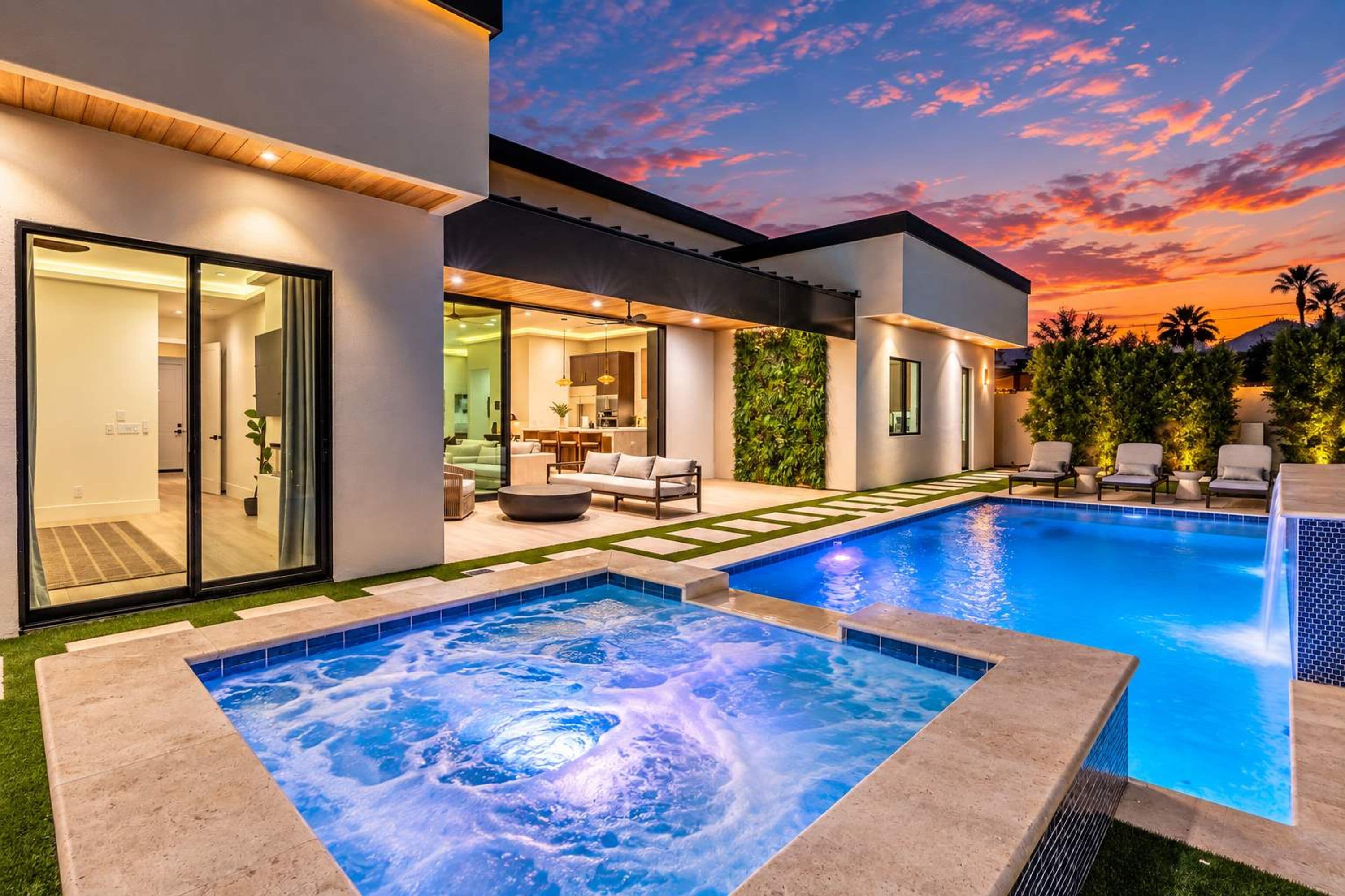 Una casa moderna con piscina, jacuzzi y un patio con mobiliario exterior.