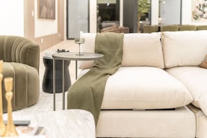 A modern living room with a sectional sofa, a small round table, and a glass of wine. - Mariposa Social Luxe Old Town Villa (Scottsdale)