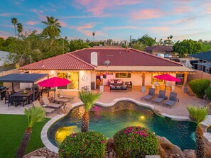 Ein Wohnhaus mit Swimmingpool, Sitzgelegenheiten im Freien und einer überdachten Terrasse.