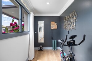 A modern home interior with a large window, a mirror, a wall-mounted exercise bike, and a decorative wall piece. - NEW Luna Lunera Gameroom Pool Sleeps 14 (Scottsdale)