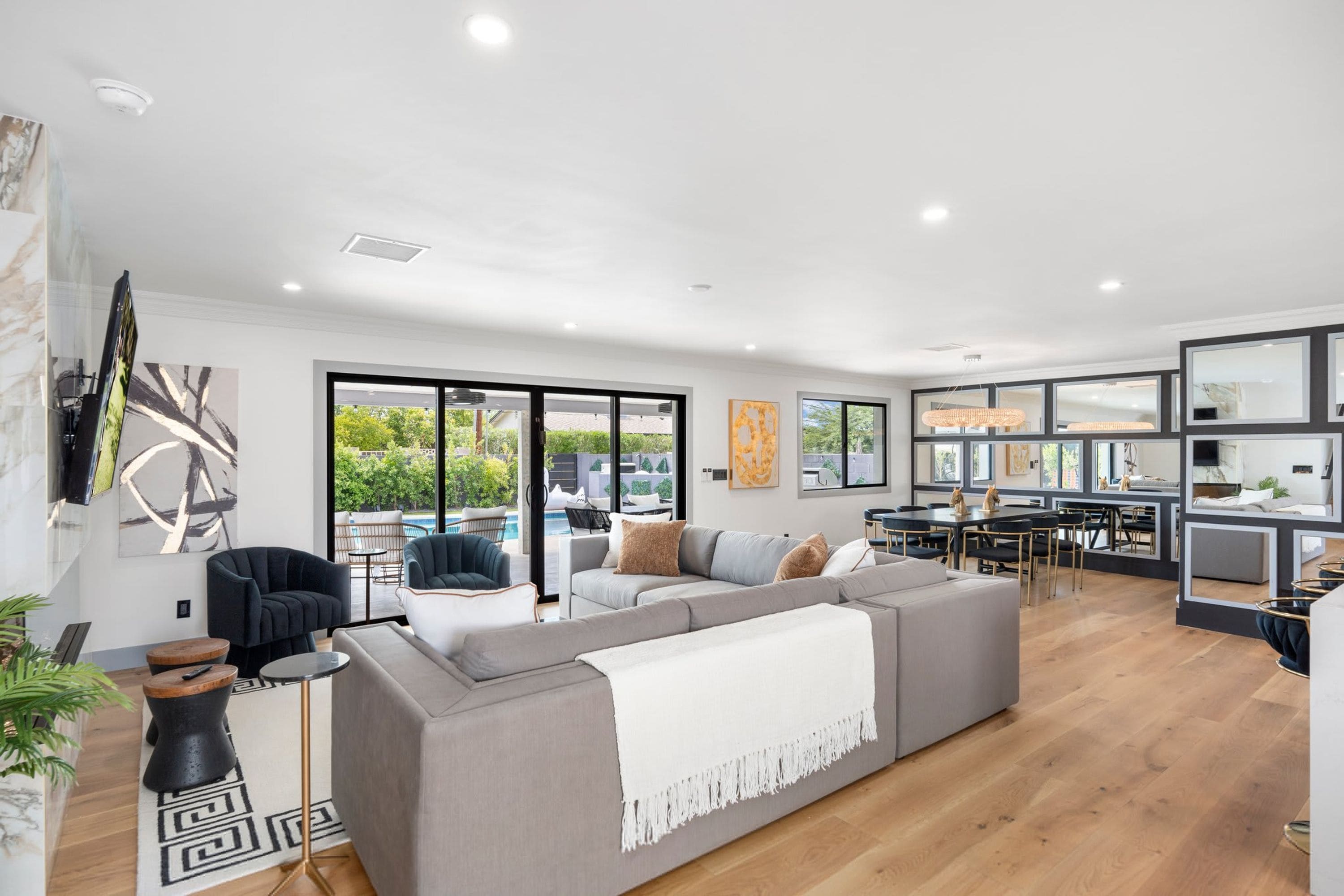 A modern living room with a grey sectional sofa, a coffee table, and a TV mounted on the wall.