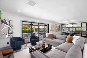 A modern living room with a grey sofa, blue armchairs, and a glass coffee table. - NEW Luna Lunera Gameroom Pool Sleeps 14 (Scottsdale)