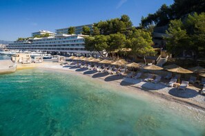 Hotel aan het strand met een zwembad, ligbedden en parasols.