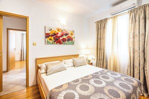 A hotel room with a bed, a painting of flowers, a lamp, and curtains. - A8 - Apartment with terrace and the sea view, 4 min walk to the beach (Žrnovnica)