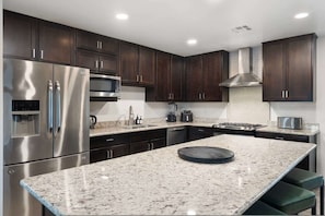 A modern kitchen with dark wood cabinets, stainless steel appliances, and a granite countertop. - NEW The Tipsy Cactus Old Town Oasis Pool Bar Putt (Scottsdale)