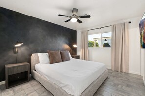 A modern bedroom with a large bed, two bedside lamps, a ceiling fan, and a window with curtains. - NEW The Tipsy Cactus Old Town Oasis Pool Bar Putt (Scottsdale)