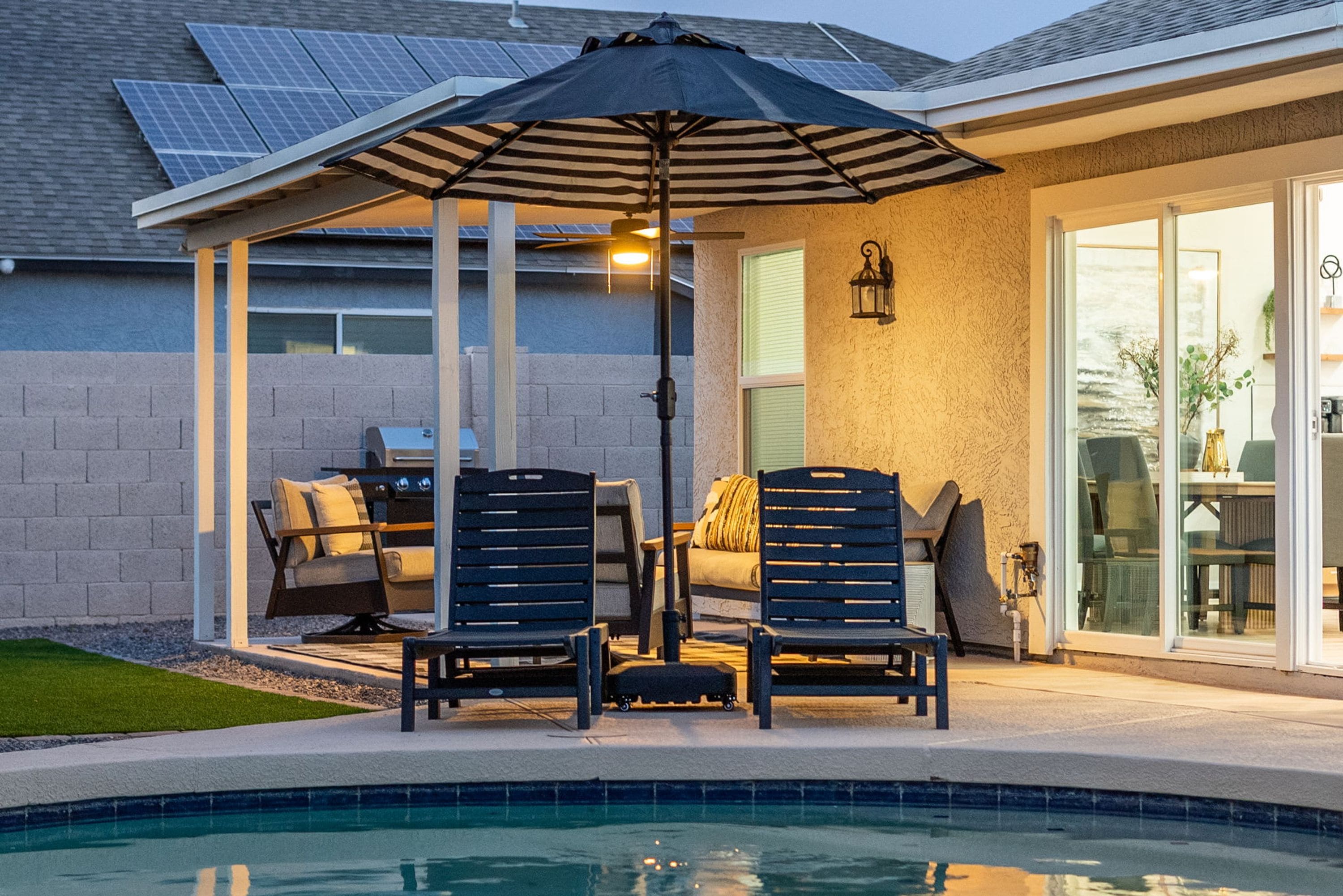 A poolside area with two chairs, a table, and an umbrella.