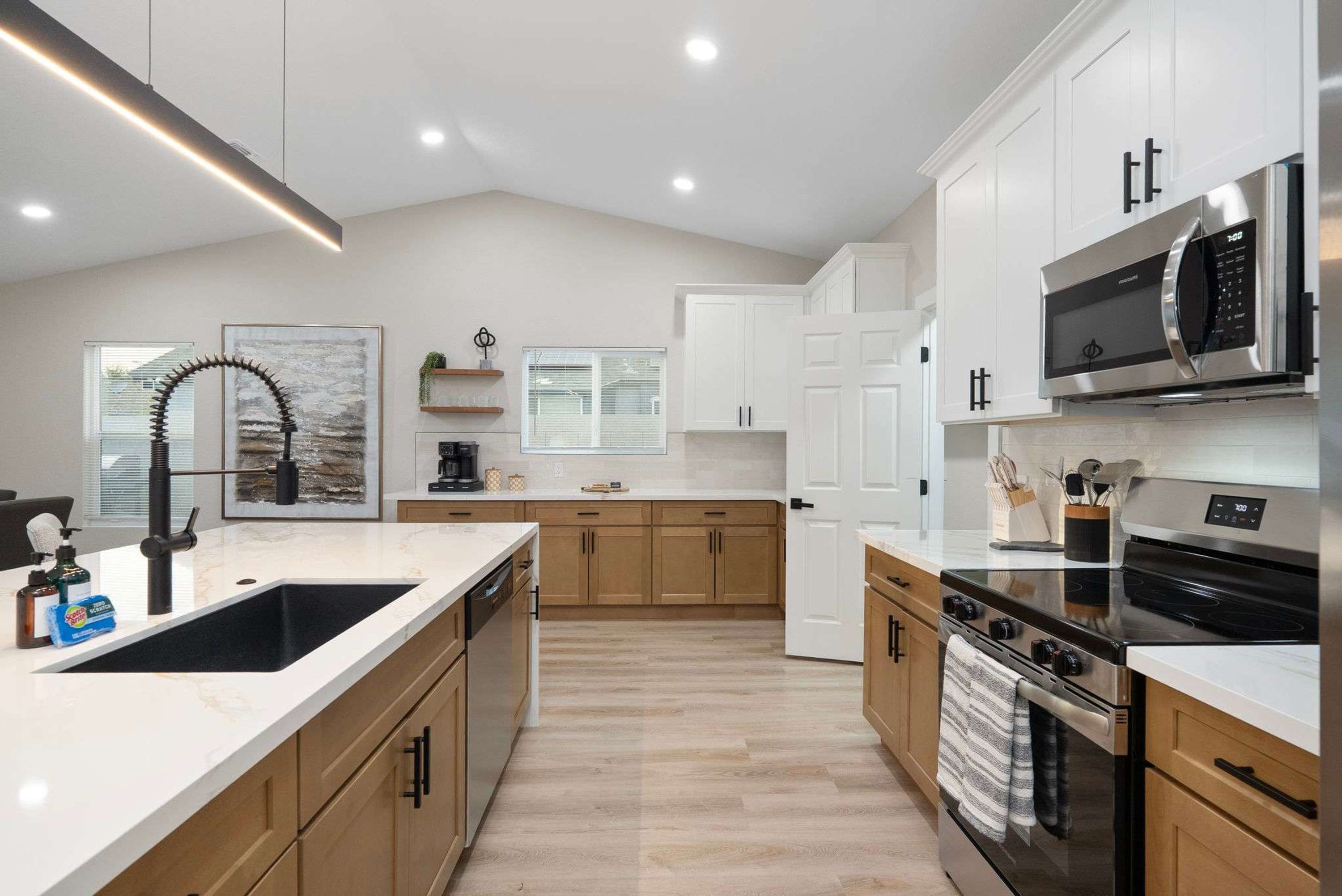 A modern kitchen with a large island, stainless steel appliances, and wooden cabinets.
