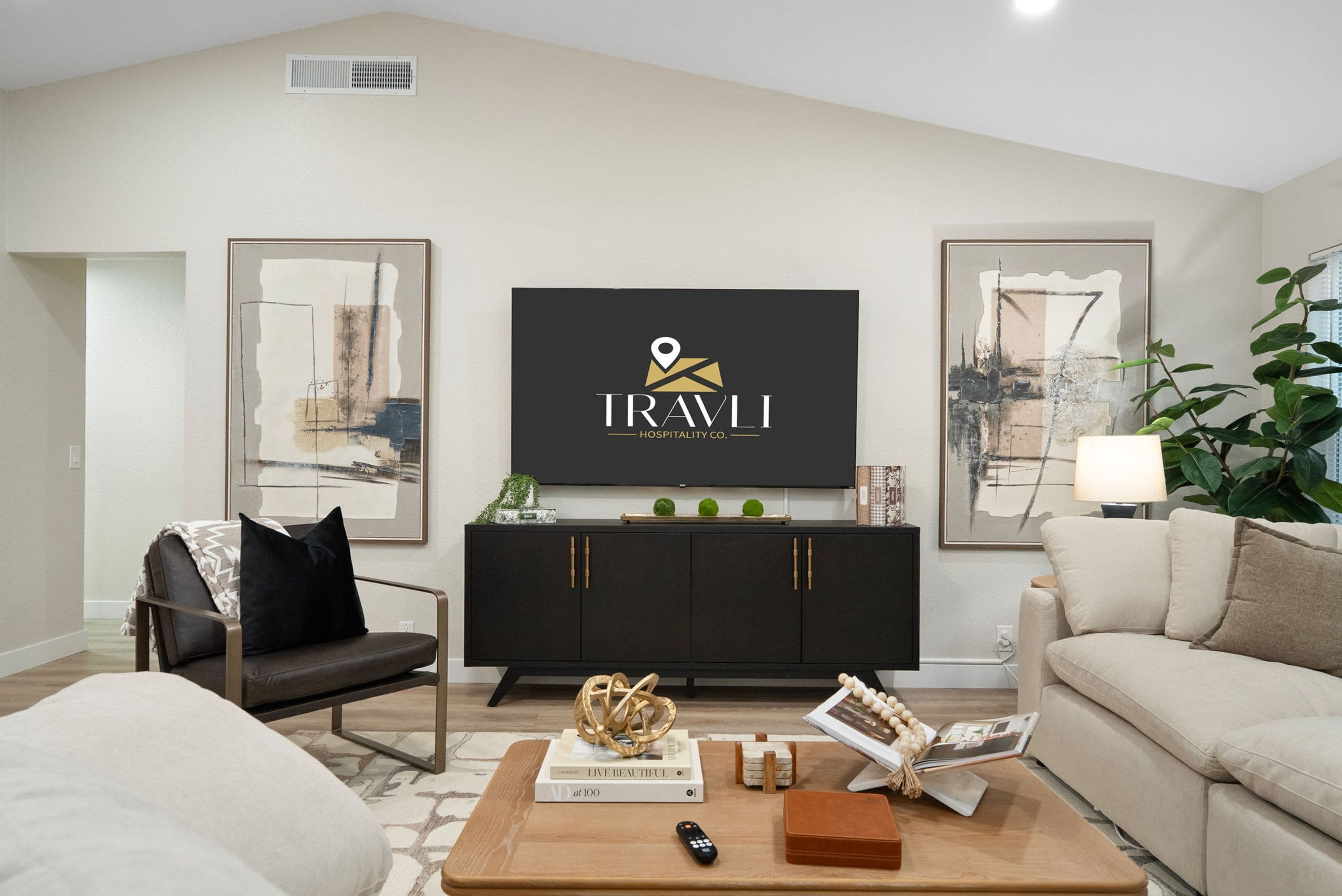 A modern living room with a black entertainment unit, a sofa, a coffee table, and two framed abstract paintings.