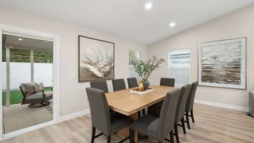 Un coin repas avec une table en bois, six chaises et deux tableaux abstraits accrochés aux murs.