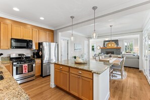 A modern kitchen with wooden cabinets, stainless steel appliances, and a central island. - Seabrook All Decked Out | Hot Tub, Dog Friendly, Sleeps 9, Pool Access (Pacific Beach)