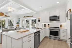 A modern kitchen with white cabinetry, stainless steel appliances, and a central island. - Seabrook Lumber Yard | Dog Friendly, Town Center, Pool Access, Sleeps 2 (Pacific Beach)