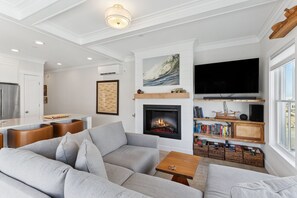A modern living room with a fireplace, a television, and a bookshelf. - Seabrook Lumber Yard | Dog Friendly, Town Center, Pool Access, Sleeps 2 (Pacific Beach)