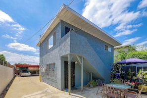 A two-story building with a flat roof, a visible garage door, and a small outdoor seating area with a table and chairs. - Quaint & Cozy Hideaway! 15 Min to LAX (Los Angeles)