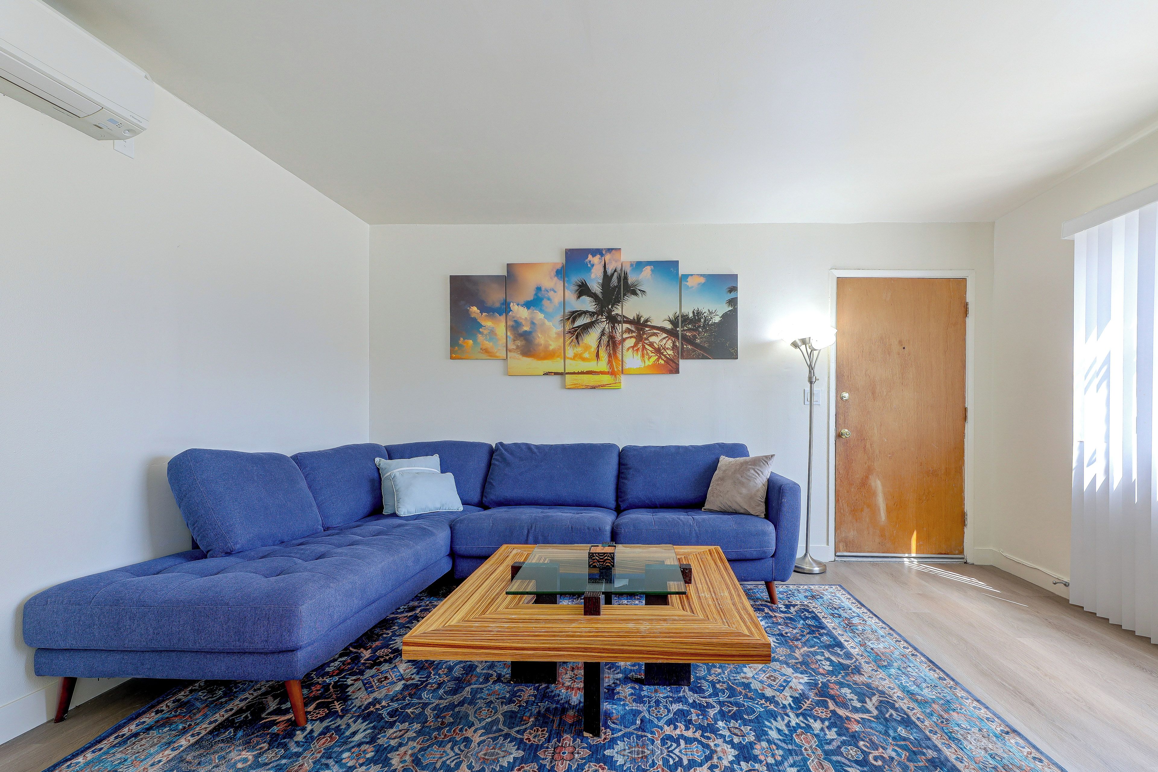 A living room with a blue sofa, a coffee table, and a patterned rug.