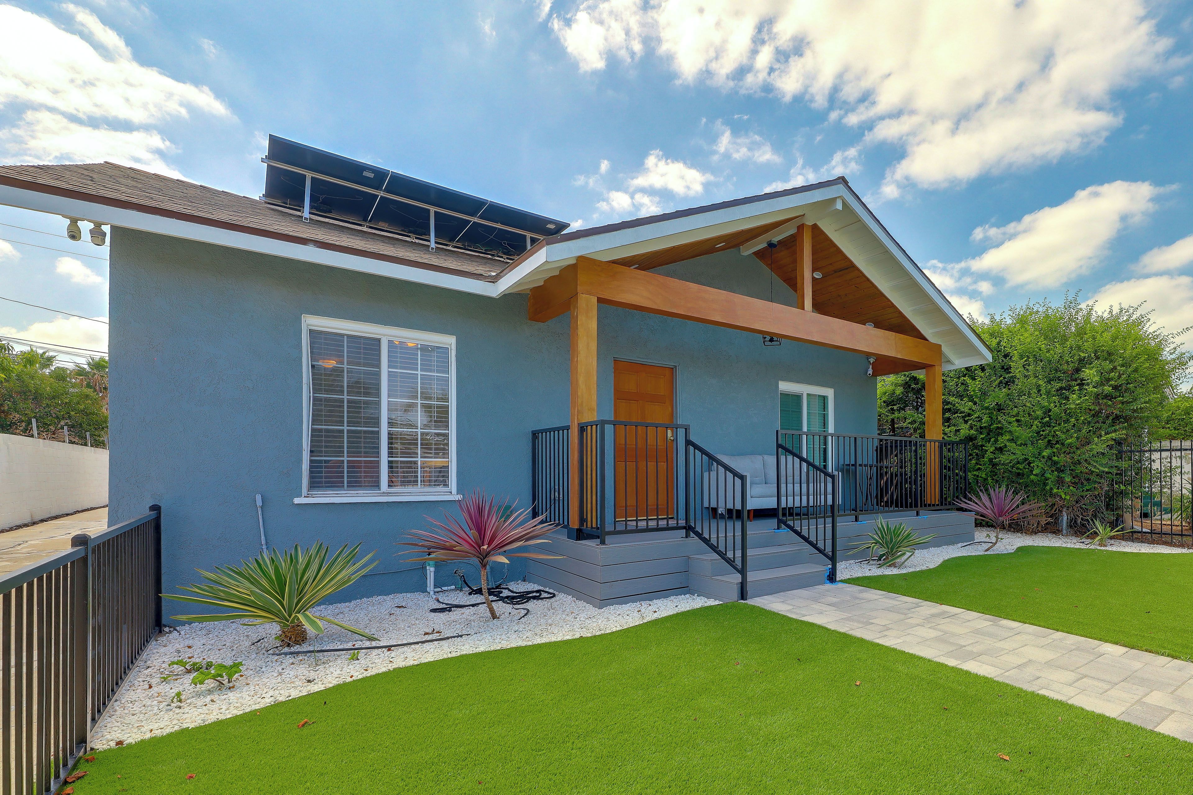 A modern house with a covered porch, a solar panel, and a well-maintained lawn.