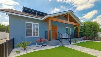 A modern house with a covered porch, a solar panel, and a well-maintained lawn.