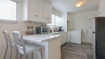 A kitchen with white cabinets, a microwave, a toaster, and a refrigerator.