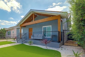 A two-story house with a covered porch, a fenced yard, and a well-maintained lawn. - LA Home w/ Porch, 3 Mi to Stadiums! (Los Angeles)