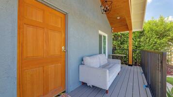 A wooden door, a white sofa, and a wooden deck with a railing.