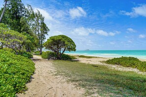 A sandy path leading to a beach with lush greenery and a clear blue sky. - Waimanalo Beach Cottages: Unit 6 + Views! (Waimanalo)
