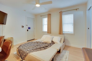 Ein Schlafzimmer mit Bett, Schreibtisch, Stuhl, Deckenventilator und Fernseher an der Wand.